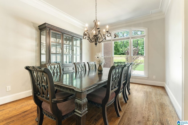 dining room with ornamental molding, plenty of natural light, wood-type flooring, and a notable chandelier