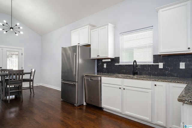 kitchen featuring dark stone counters, white cabinets, sink, stainless steel appliances, and a chandelier