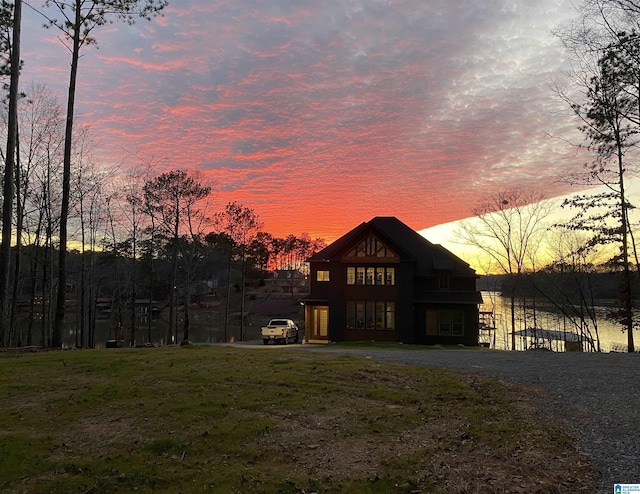 back house at dusk with a yard and a water view