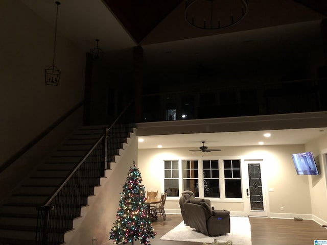 living room with hardwood / wood-style floors, ceiling fan, and a high ceiling