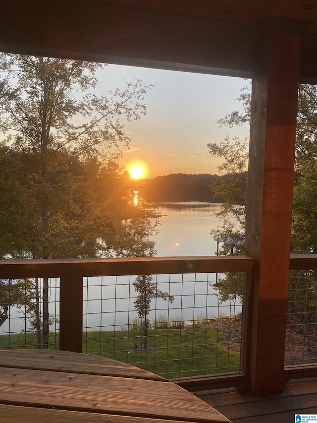 deck at dusk featuring a water view