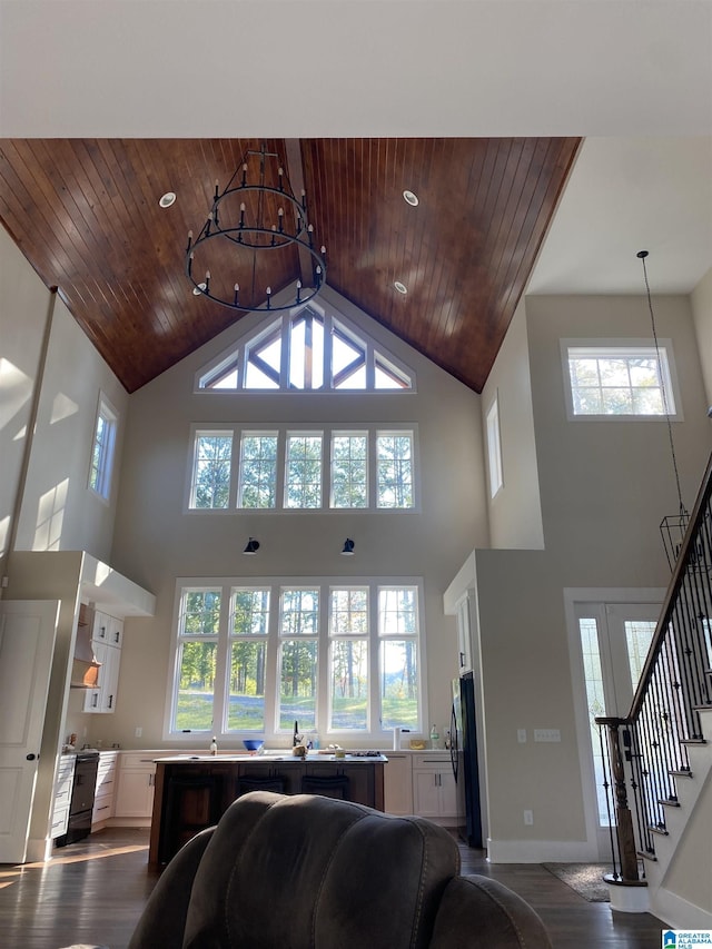 living room with a notable chandelier, dark hardwood / wood-style flooring, high vaulted ceiling, and wooden ceiling