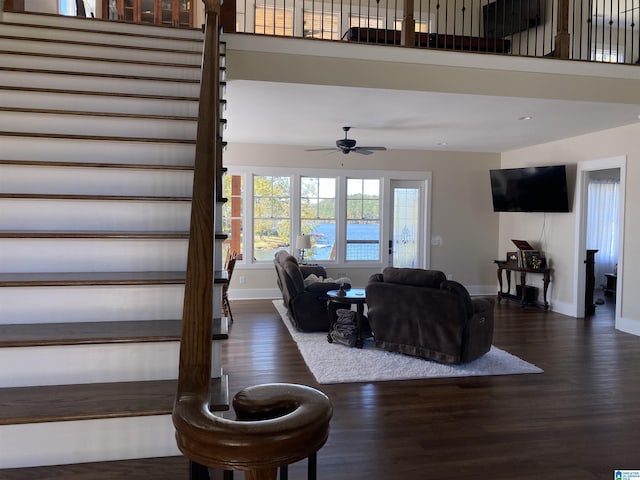 living room with a towering ceiling, dark wood-type flooring, and ceiling fan