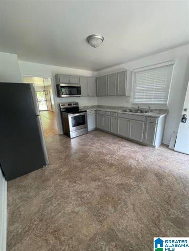 kitchen with stainless steel appliances, gray cabinets, and sink