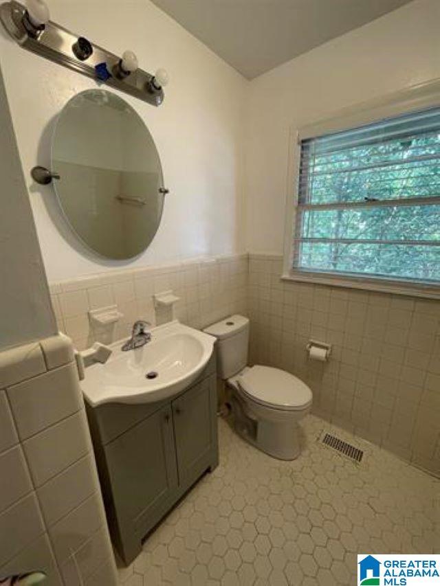 bathroom featuring tile patterned floors, vanity, tile walls, and toilet