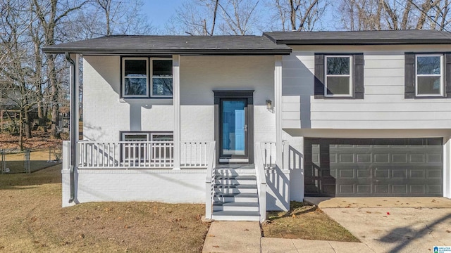 raised ranch with a porch, a garage, and a front lawn