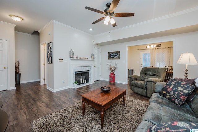 living room featuring ceiling fan, a premium fireplace, dark hardwood / wood-style floors, and ornamental molding