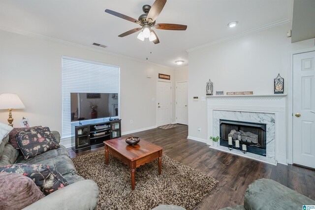 living room featuring a premium fireplace, dark hardwood / wood-style flooring, ceiling fan, and crown molding