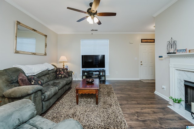 living room with crown molding, ceiling fan, dark wood-type flooring, and a premium fireplace