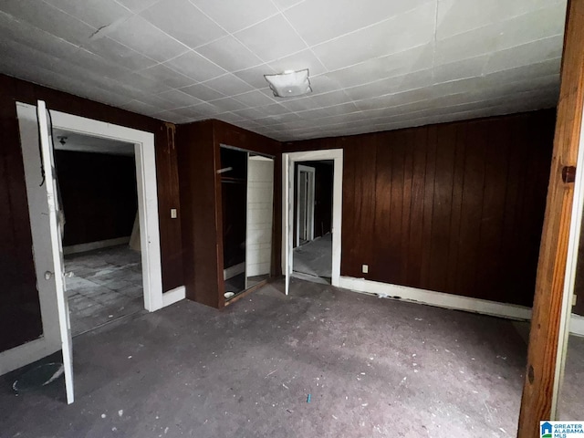 unfurnished bedroom featuring a closet and wood walls