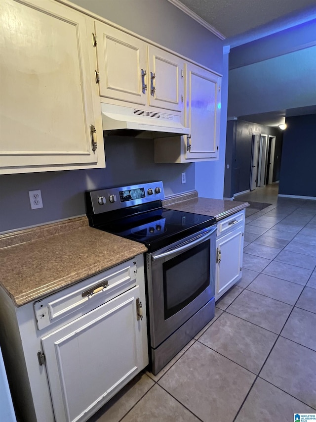 kitchen featuring white cabinets, stainless steel electric range, light tile patterned flooring, and ornamental molding