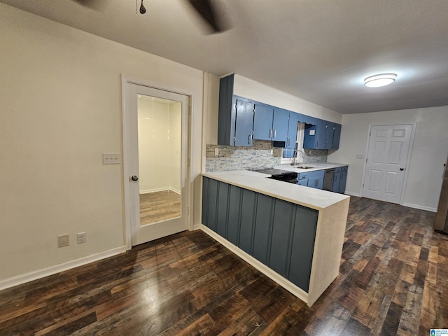 kitchen with backsplash, blue cabinets, sink, dark hardwood / wood-style flooring, and kitchen peninsula