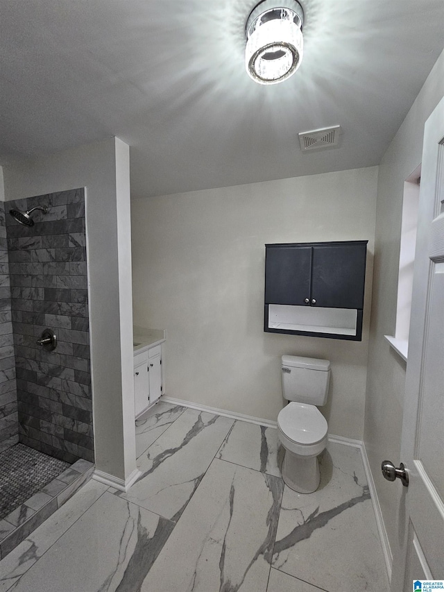 bathroom with vanity, toilet, and tiled shower