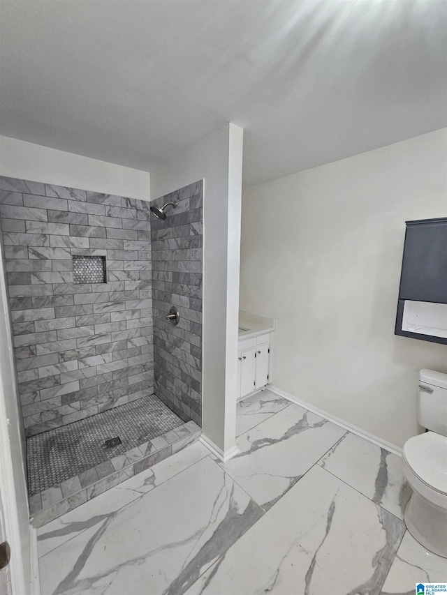 bathroom with a tile shower, vanity, and toilet