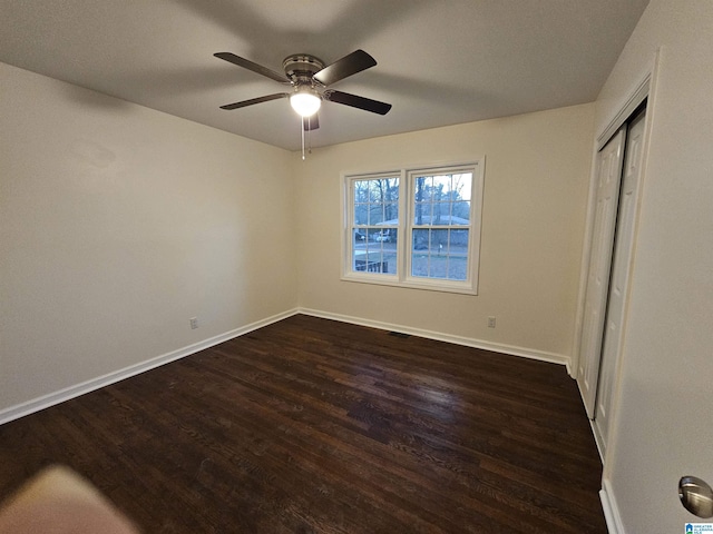 unfurnished bedroom featuring ceiling fan, a closet, and dark wood-type flooring