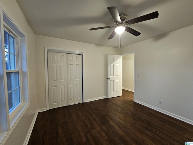 unfurnished bedroom with ceiling fan, a closet, and dark wood-type flooring