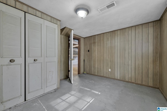 unfurnished bedroom with wood walls and a closet