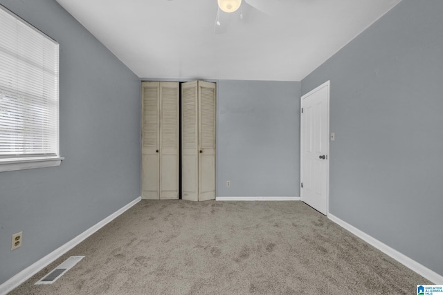 unfurnished bedroom featuring ceiling fan, light colored carpet, and a closet