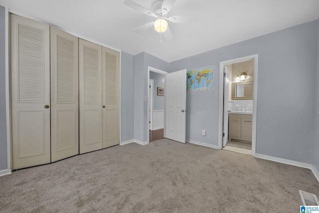 unfurnished bedroom with ensuite bath, ceiling fan, a closet, and light carpet