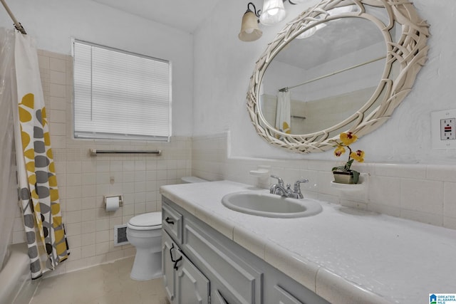 bathroom with tile patterned floors, vanity, toilet, and tile walls