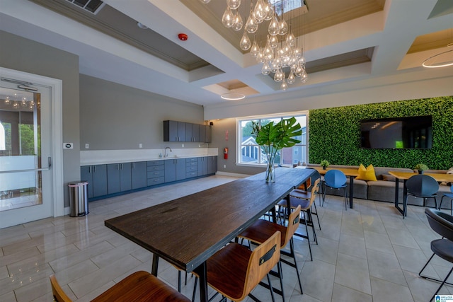 dining room with light tile patterned floors, ornamental molding, coffered ceiling, and an inviting chandelier