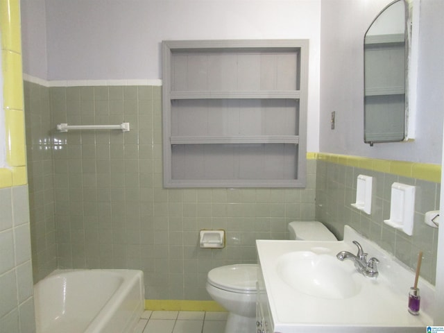 bathroom featuring vanity, tile patterned floors, toilet, a tub to relax in, and tile walls