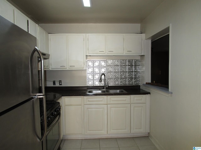 kitchen with white cabinets, sink, light tile patterned floors, range, and stainless steel refrigerator