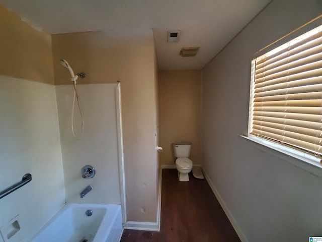 bathroom with wood-type flooring, bathing tub / shower combination, and toilet