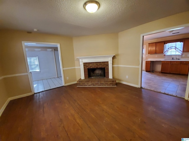 unfurnished living room with a fireplace, dark hardwood / wood-style flooring, and a textured ceiling