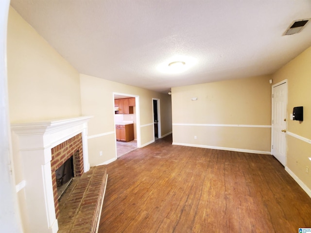 unfurnished living room featuring a textured ceiling, a fireplace, and wood-type flooring