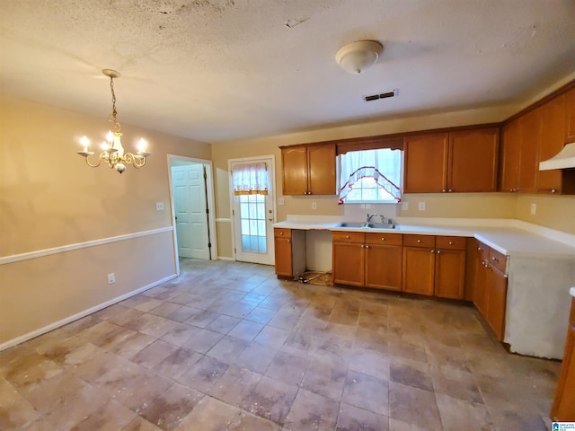 kitchen with sink, pendant lighting, a notable chandelier, and a textured ceiling