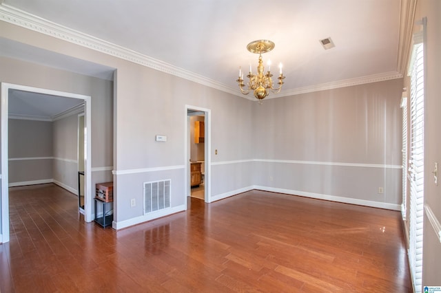 spare room featuring wood-type flooring, crown molding, and a notable chandelier