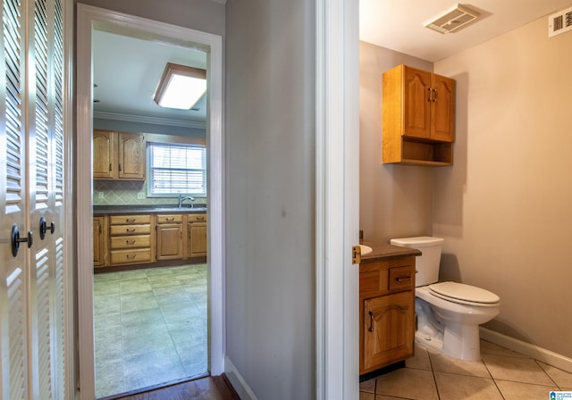 bathroom with decorative backsplash, ornamental molding, vanity, tile patterned flooring, and toilet