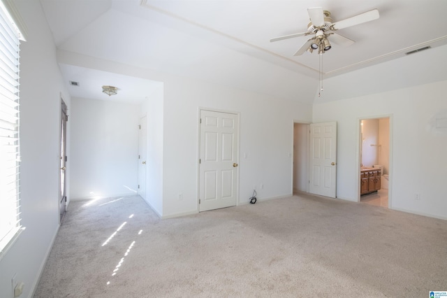 unfurnished bedroom featuring ensuite bathroom, vaulted ceiling, ceiling fan, and light colored carpet