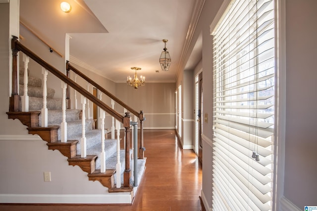 foyer with crown molding, a chandelier, and wood-type flooring