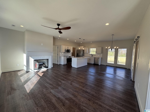 unfurnished living room with ceiling fan with notable chandelier, dark hardwood / wood-style flooring, and sink