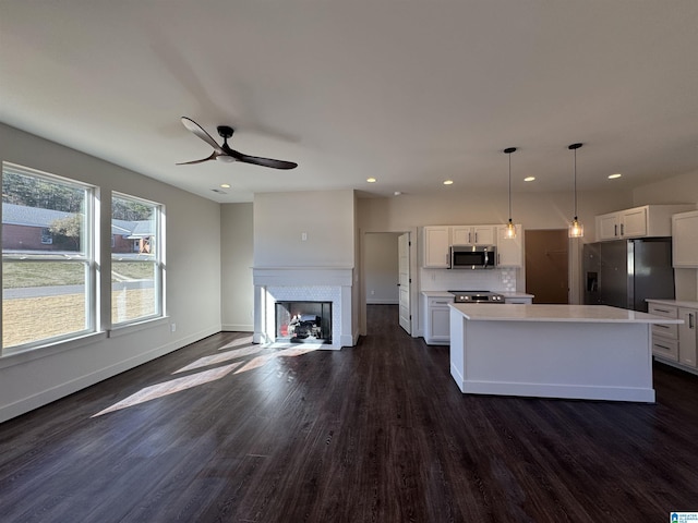 kitchen with a center island, white cabinets, stainless steel appliances, and decorative light fixtures