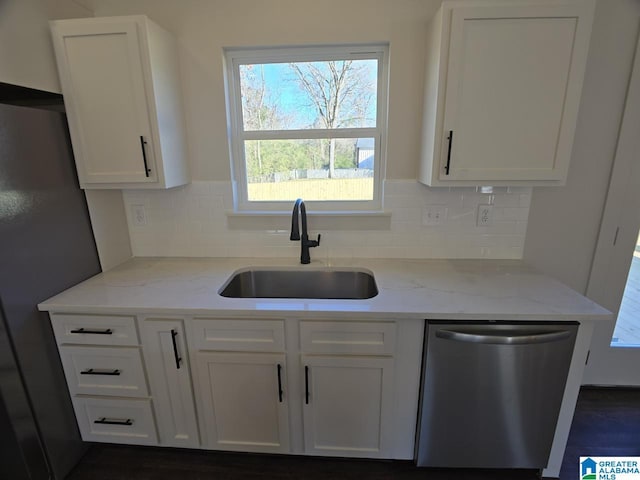 kitchen with white cabinets, sink, light stone countertops, tasteful backsplash, and stainless steel appliances