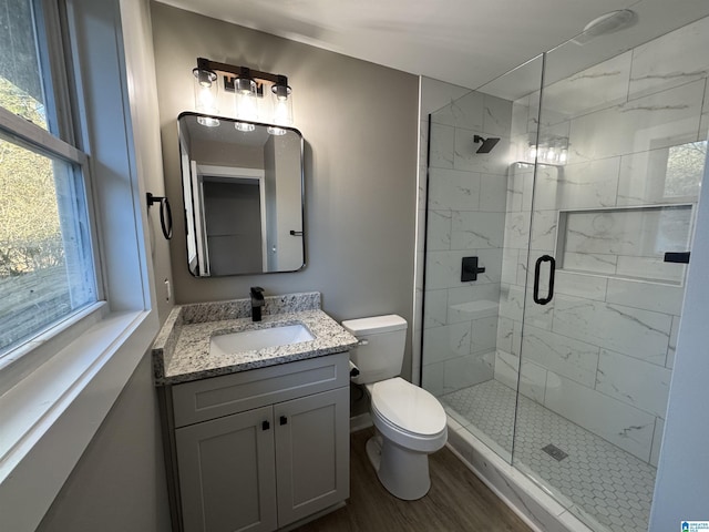 bathroom with a healthy amount of sunlight, a shower with door, hardwood / wood-style flooring, and vanity