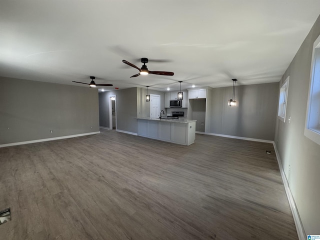 unfurnished living room with ceiling fan, sink, and hardwood / wood-style floors