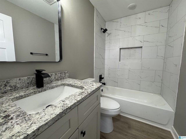 full bathroom with hardwood / wood-style floors, toilet, vanity, and tiled shower / bath combo