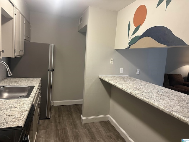 kitchen with white cabinets, dark hardwood / wood-style flooring, light stone countertops, and sink