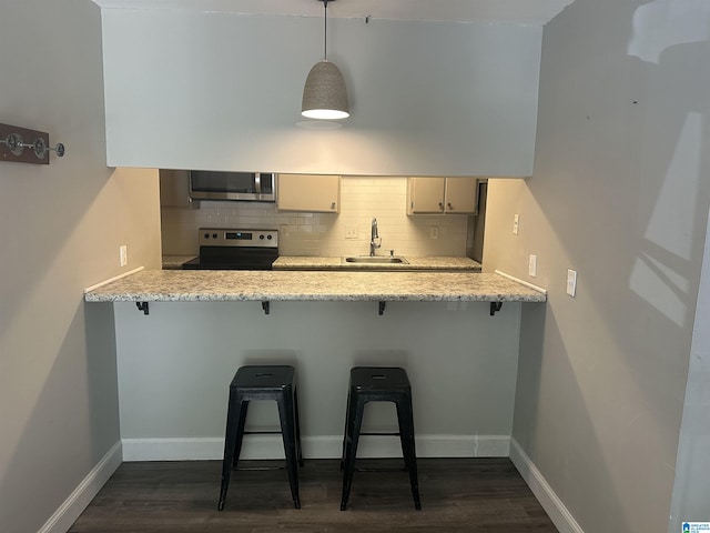 kitchen with a kitchen breakfast bar, range with electric cooktop, hanging light fixtures, and sink