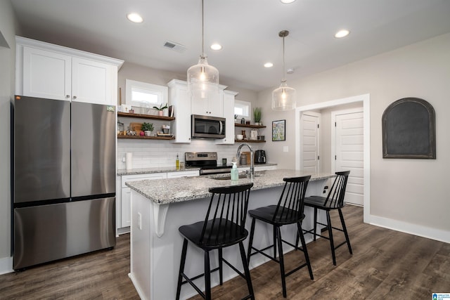 kitchen featuring appliances with stainless steel finishes, sink, pendant lighting, a center island with sink, and white cabinetry