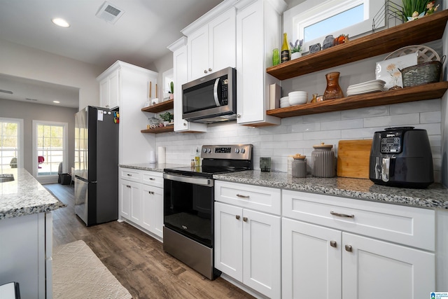 kitchen featuring white cabinets, dark hardwood / wood-style floors, tasteful backsplash, light stone counters, and stainless steel appliances