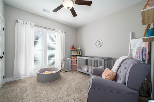 bedroom featuring carpet, ceiling fan, and a nursery area