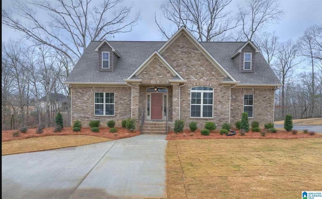 craftsman-style house with brick siding, roof with shingles, and a front yard