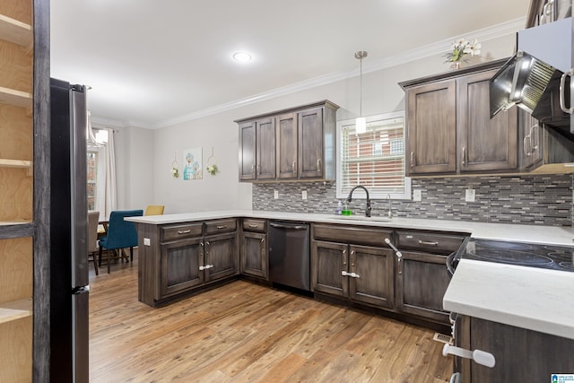 kitchen featuring a peninsula, light wood-style flooring, a sink, appliances with stainless steel finishes, and crown molding