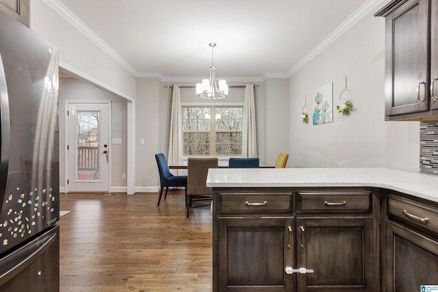 kitchen featuring a notable chandelier, dark brown cabinets, freestanding refrigerator, and wood finished floors