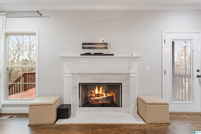 room details featuring wood finished floors, visible vents, a high end fireplace, and ornamental molding